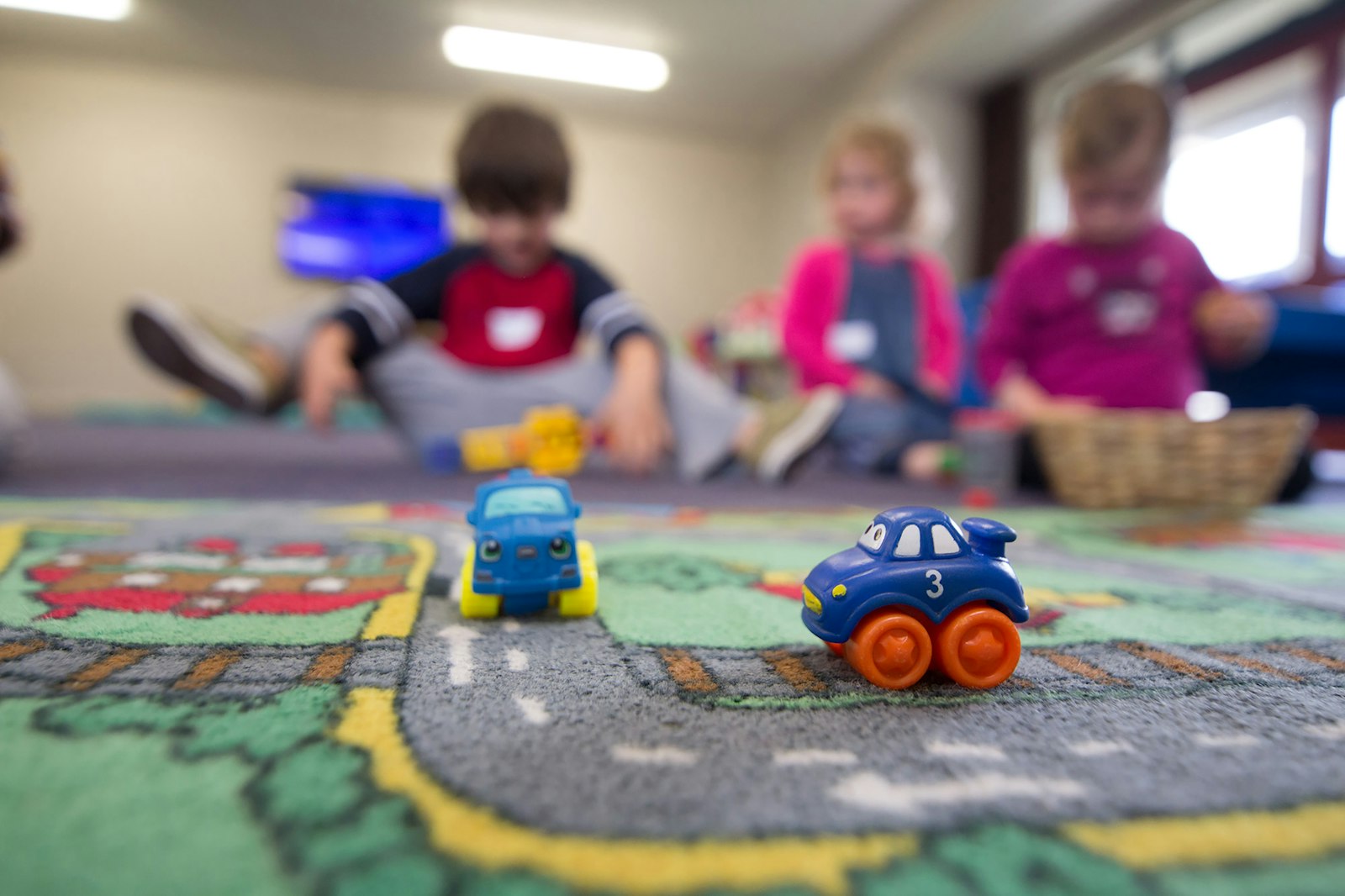 Toddlers playing with toy cars at a daycare