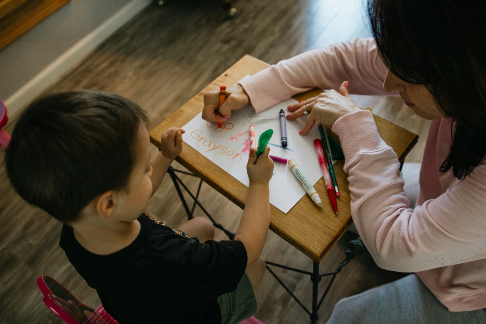 A teacher helping a young child write at a child care center